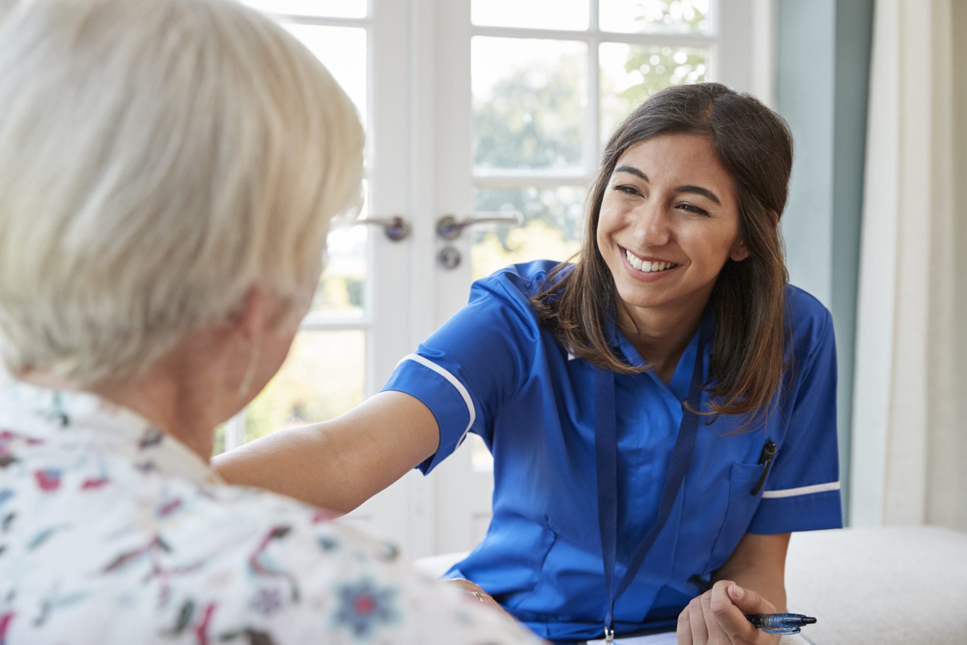 Young care nurse on home visit comforting senior woman Young care nurse on home visit comforting senior woman